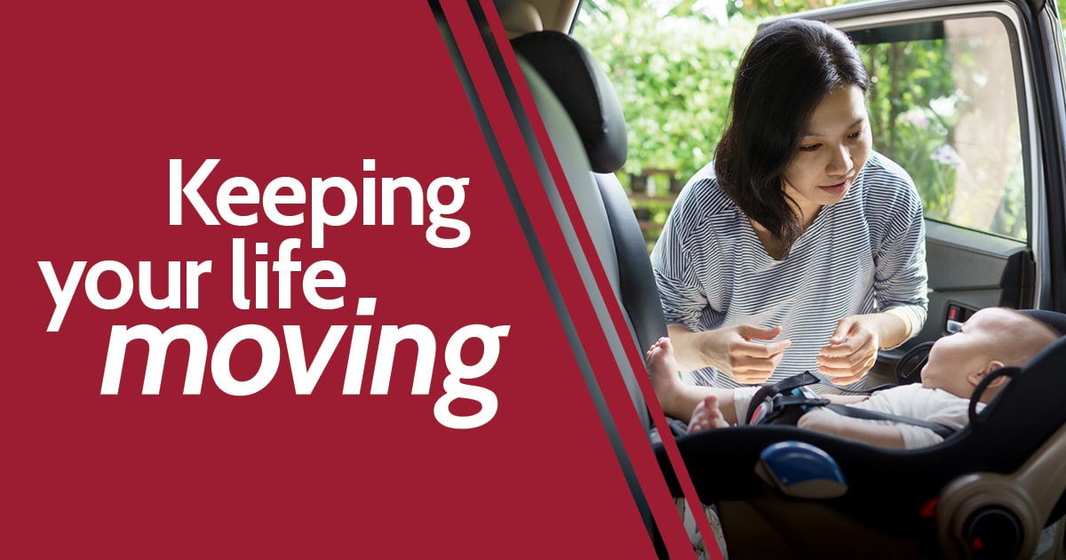 Keeping Your Life Moving - A happy mother is strapping her baby into a car seat in the back of her vehicle