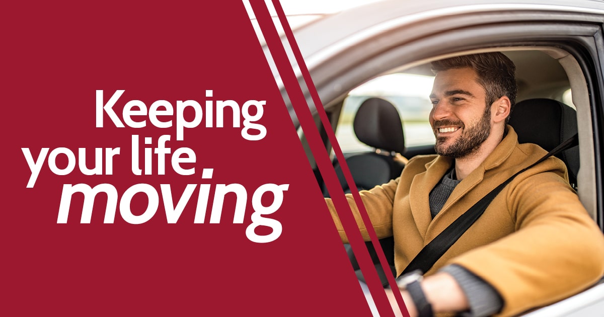 Young man smiling while driving his car on the road.